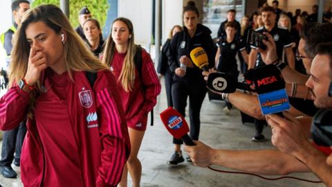 Spain players pass journalists who hold out microphones