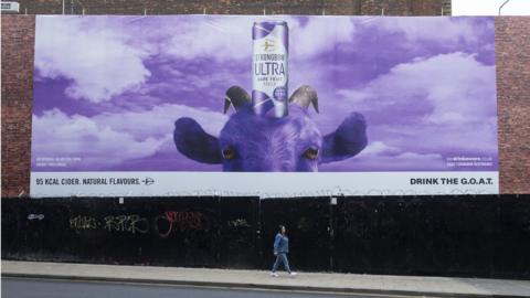 A woman walking past a giant billboard advertisement in Manchester in May of this year