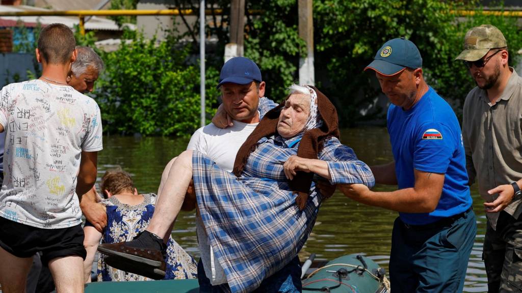 A man carrying an elderly woman in flooded Kherson