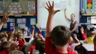 Children hold their hands up during a lesson in a school classroom