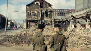 Soldiers stand close to the scene of a bomb attack that destroyed buildings during the Troubles