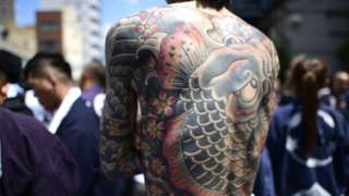 Participant with Japanese tattoo is seen in the street of Asakusa during Sanja Festival on May 19, 2019 in Tokyo, Japan