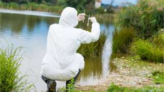 Person holding up water samples next to lake