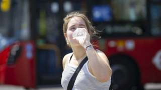 Woman drinks from water bottle during hot weather