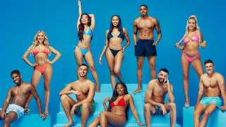 André Furtado, Molly Marsh, George Fensom, Ruchee Gurung, Ella Thomas, Catherine Agbaje, Tyrique Hyde, Mehdi Edno, Jess Harding and Mitchel Taylor all in swimwear, posing in front of a blue background