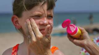 Child having sunscreen put on face