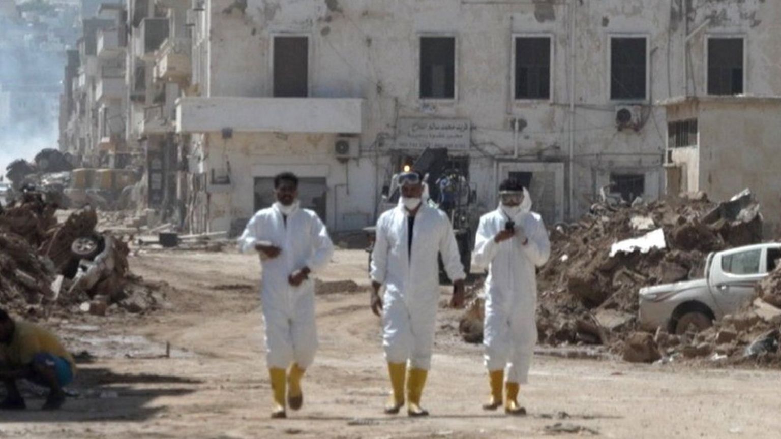 Men in hazmat suits walking through Derna