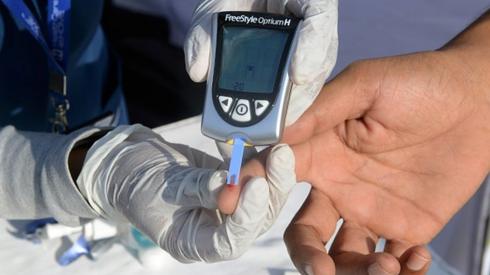 A nurse collects a blood sample using a glucometer at a free diabetic health check-up camp