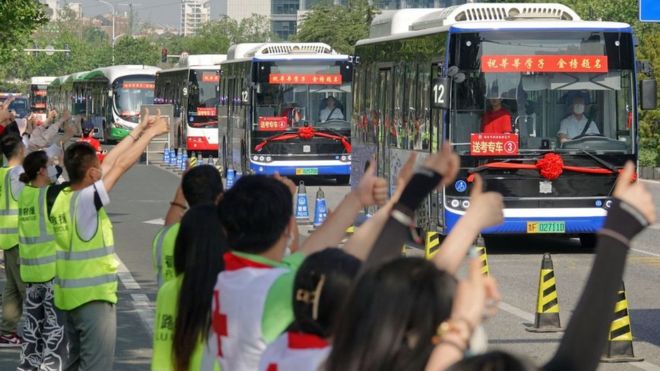 People gesture to buses transferring students to attend the National College Entrance Examination (NCEE), known as "gaokao", in Yantai, in China's eastern Shandong province on June 7, 2023.