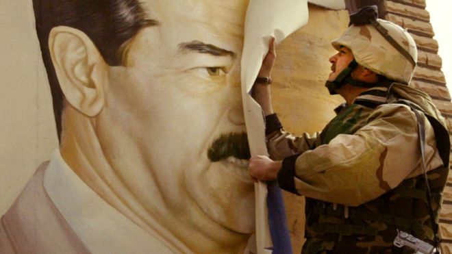2003 में एक अमेरिकी सेना अधिकारी ने इराक़ में सद्दाम हुसैन के एक पोस्टर को फाड़ दिया