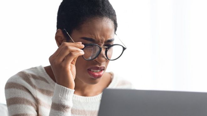 Femme avec des lunettes devant son ordinateur
