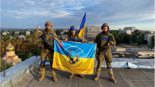 Ukrainian soldiers hold a flag at a rooftop in Kupiansk, Ukraine, Sept 10, 2022