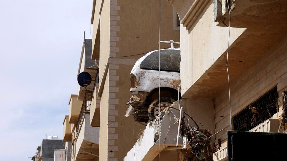 A destroyed car sits on top of a residential building following fatal floods in Dern