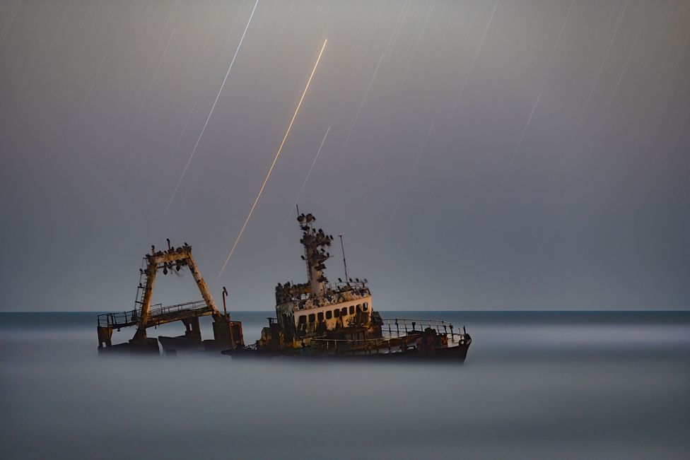 An image of a ship wrecked of the coast of Namibia at night
