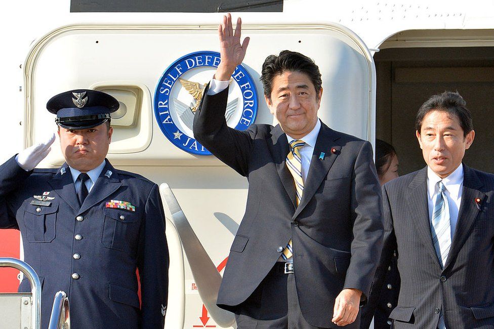 Former Japanese Prime Minister Shinzo Abe (C), accompanied by then foreign minister Fumio Kishida (R), in 2013