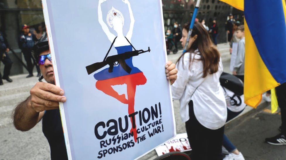 A protester in Mexico City holds a sign reading, Caution! Russian culture sponsors the war!