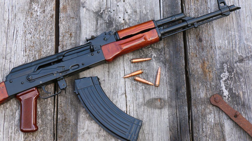 The famous Kalashnikov assault rifle with magazine and cartridges on an old, damaged board (stock photo)