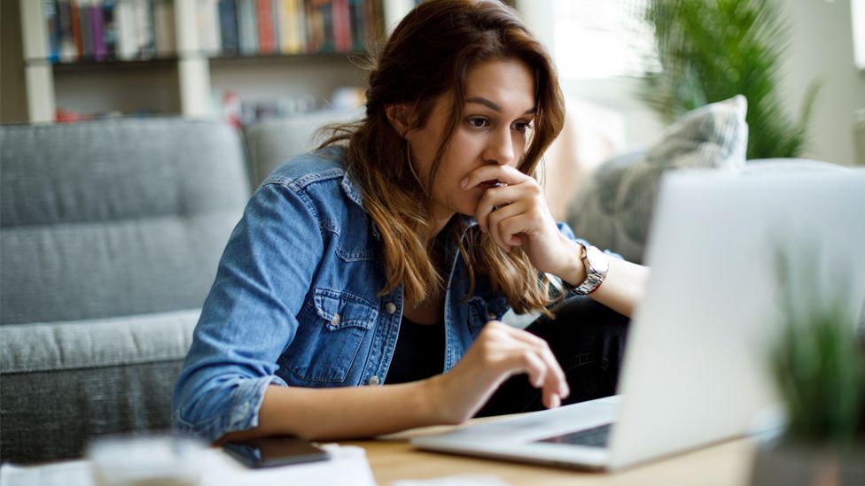 Worried woman at a laptop at home