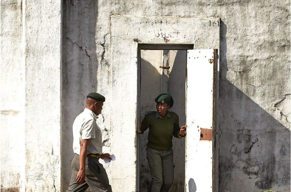 Prison guards standing by a white door at Harare Central Prison.