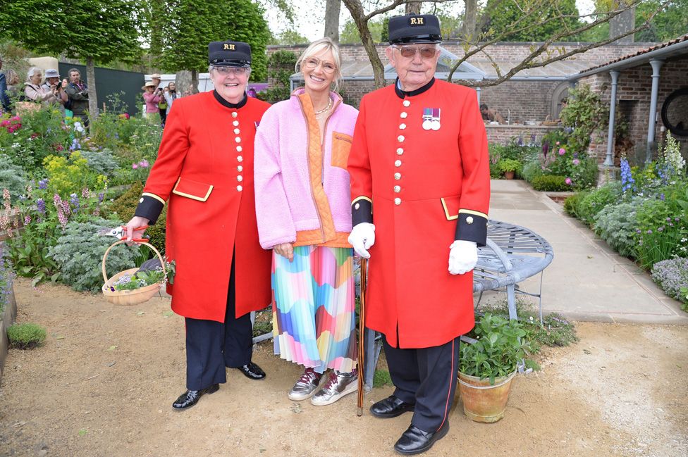 Jo Wiley poses for a photograph with two Chelsea Pensioners at the RHS Chelsea Flower Show