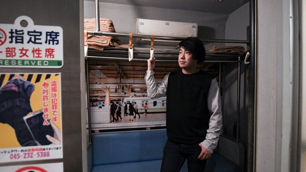 Manager of the Rush Hour sex club Hasuda Shuhei poses inside one of the club's mock-ups of a train carriage