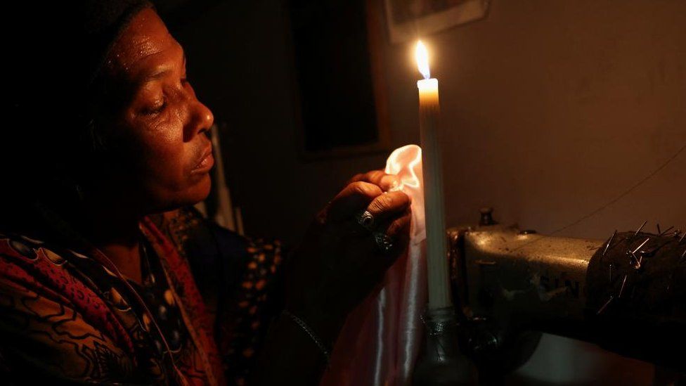 Dressmaker Faieza Caswell from Mitchells Plain sews under candlelight in her workplace, on the Cape Flats due to South Africa's struggling power utility company Eskom, implementing regular power cuts - called 'load-shedding', in Cape Town, South Africa February 11, 2023